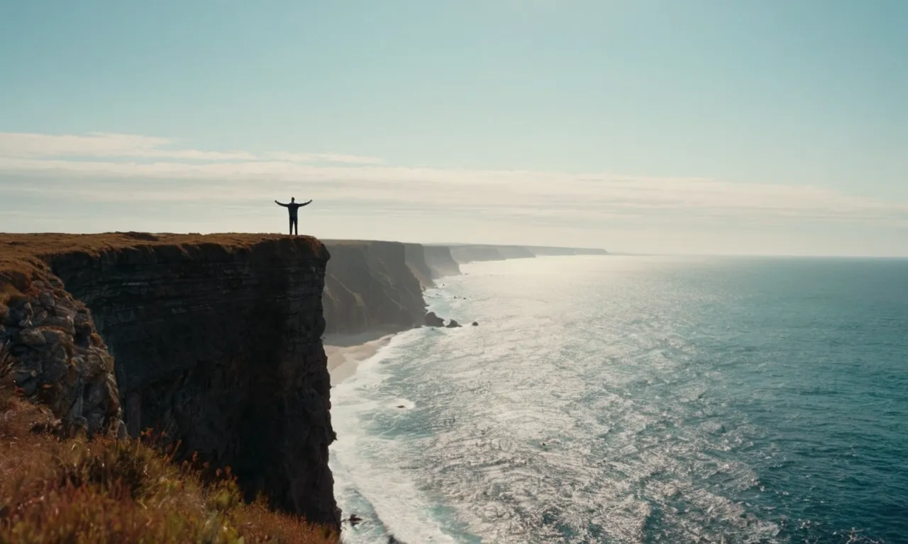 A photo capturing a person standing at the edge of a cliff, arms outstretched, facing the vast expanse of the ocean, symbolizing surrender and complete trust in God.