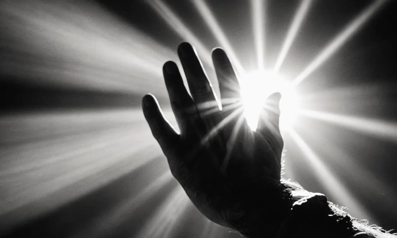 A black and white photo captures a rugged, weathered hand reaching out to touch a divine beam of light, symbolizing Jacob's timeless struggle with God.