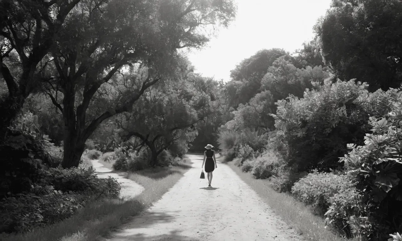 A black and white photo captures a solitary figure walking along a deserted path, surrounded by lush greenery, symbolizing a divine intervention guiding one towards a life of solitude.
