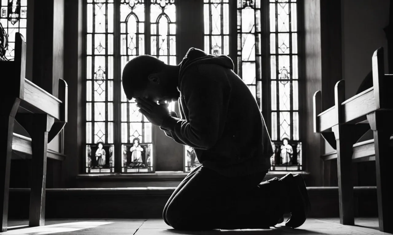A black and white image captures a person kneeling in a dimly lit church, clasping their hands together in prayer, their face illuminated by a single beam of sunlight streaming through a stained glass window.
