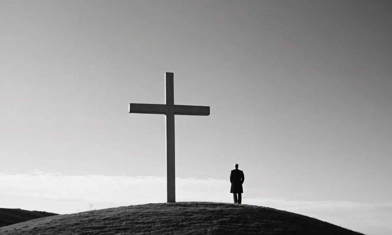 A black and white photo of a solitary figure standing before a cross on a hill, symbolizing the dreamer's contemplation of their faith and the potential significance of their dream in Christianity.