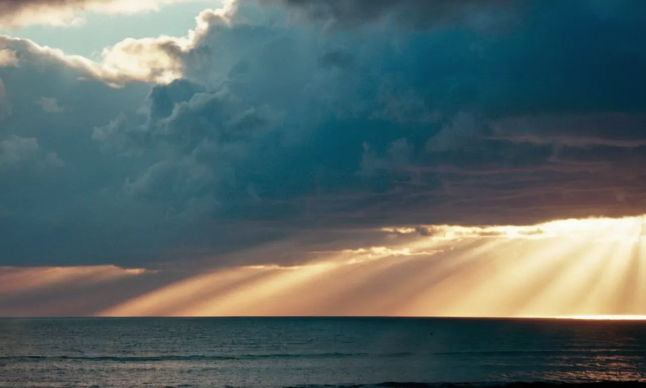 A photo of a serene sunset over a vast ocean, with rays of light breaking through the clouds, symbolizing God's promises of love, peace, guidance, provision, and eternal life.