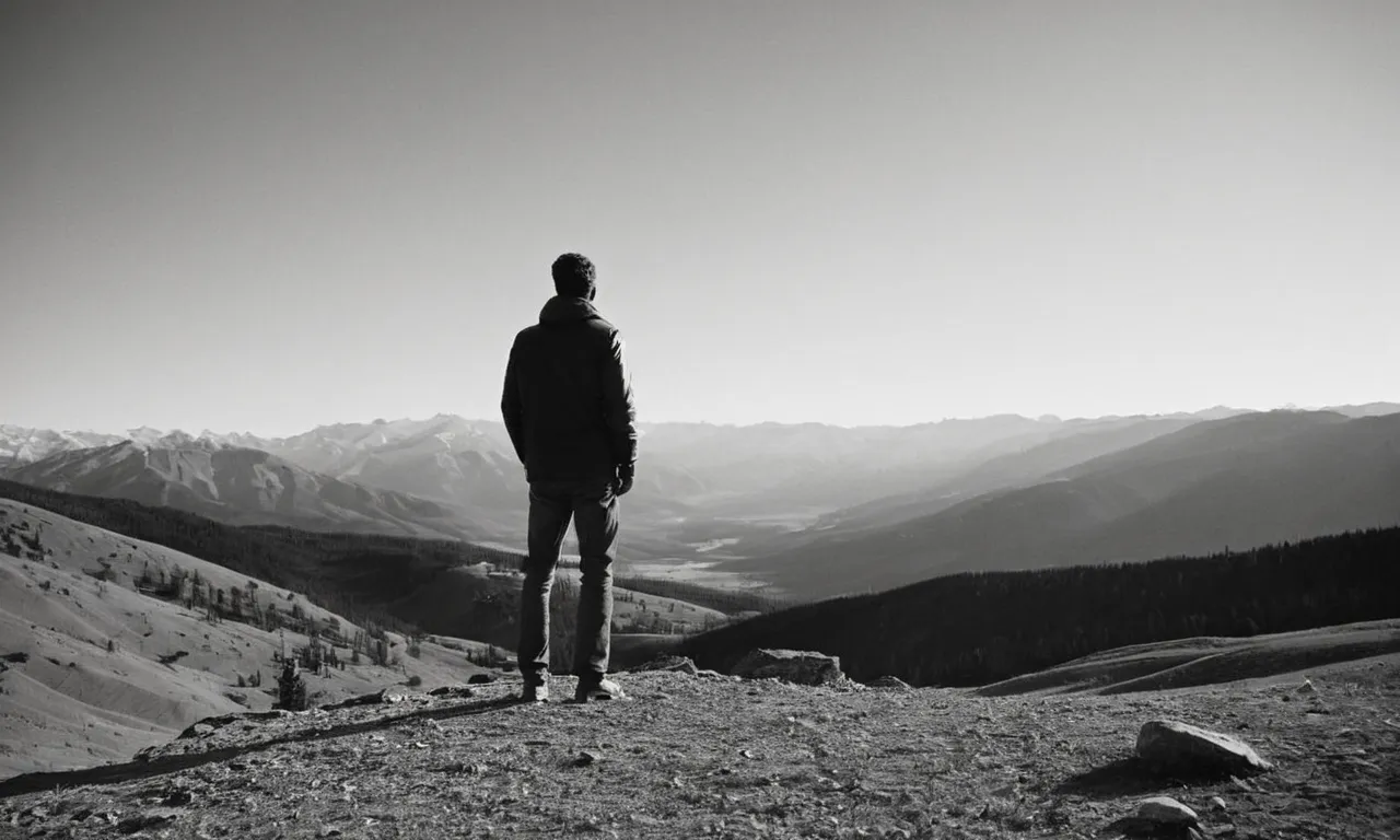 A black and white photograph captures a person standing in awe, gazing at a breathtaking landscape, symbolizing the biblical concept of "behold" - acknowledging and appreciating the wonders of God's creation.