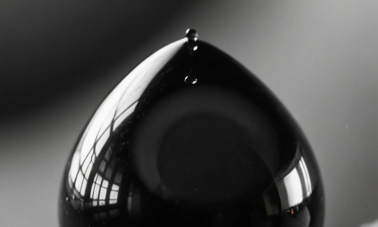 A black and white close-up photograph captures a single teardrop falling from an eye, reflecting a faint image of a comforting hand reaching down from above.