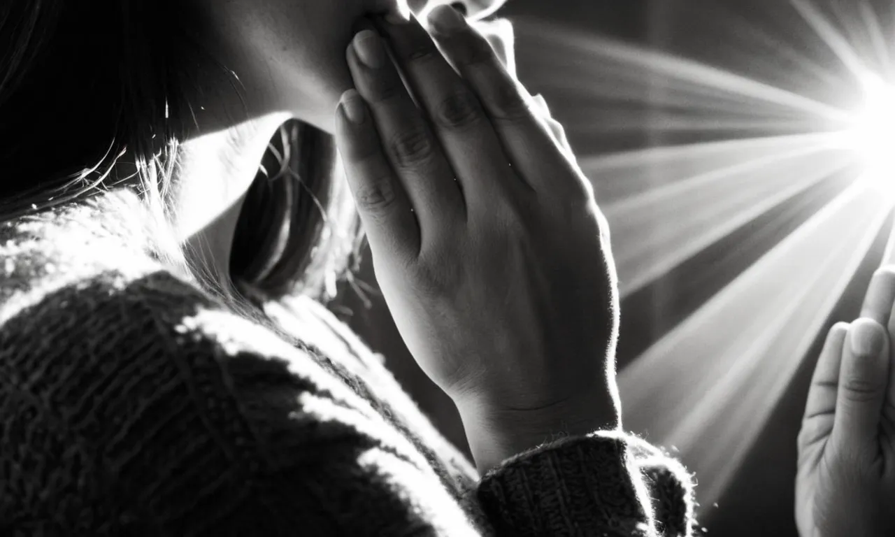 A black and white close-up of a person's hands clasped in prayer, with rays of sunlight streaming through the fingers, capturing the serene and ethereal essence of "what does God sound like."