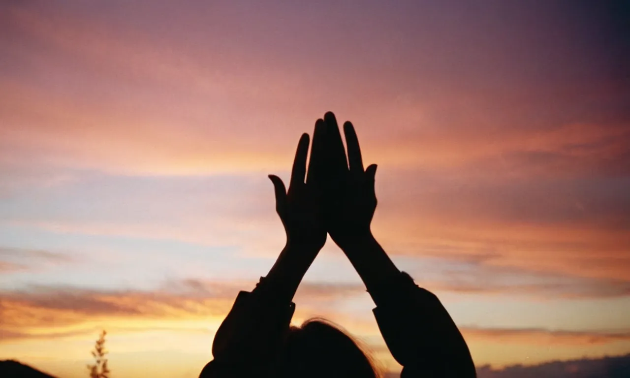 A photo capturing a person's silhouette against a vibrant sunset, with hands raised in an emphatic gesture, symbolizing the power and authority of rebuking in the name of Jesus.