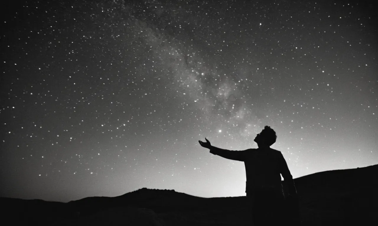 A black and white photograph captures a person gazing up at a star-filled sky, their outstretched hand reaching towards the heavens, evoking the eternal quest for the answer to "what is God's real name."