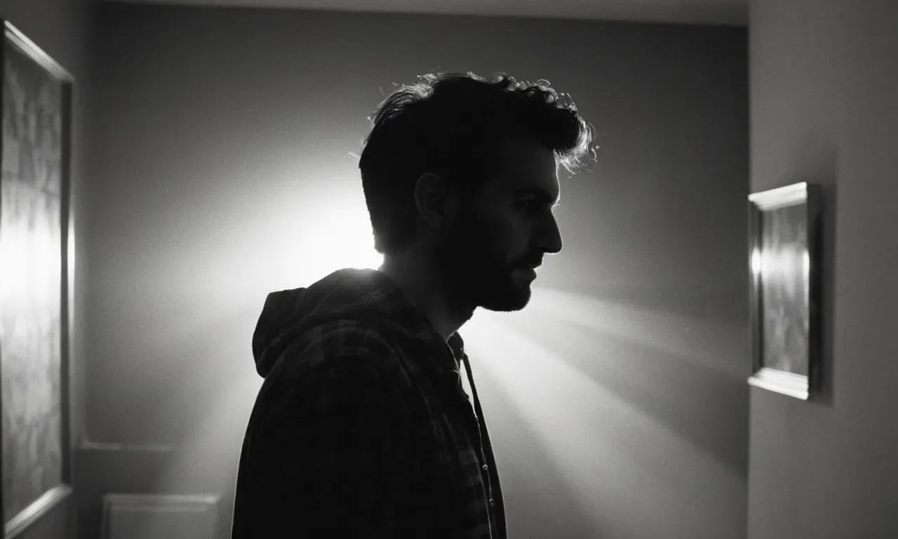 A black and white image captures a person standing in a dimly lit room, their face illuminated by a single ray of light, reflecting the struggle of finding words when confronted by someone blaming God.