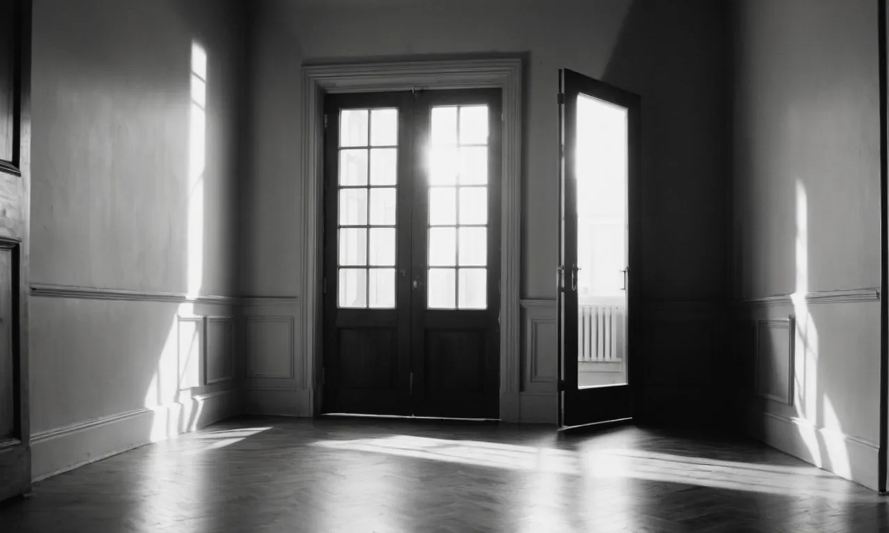 A black and white image captures an empty room, illuminated by a soft ray of light streaming through a half-opened door, symbolizing the closing of a chapter in a relationship.