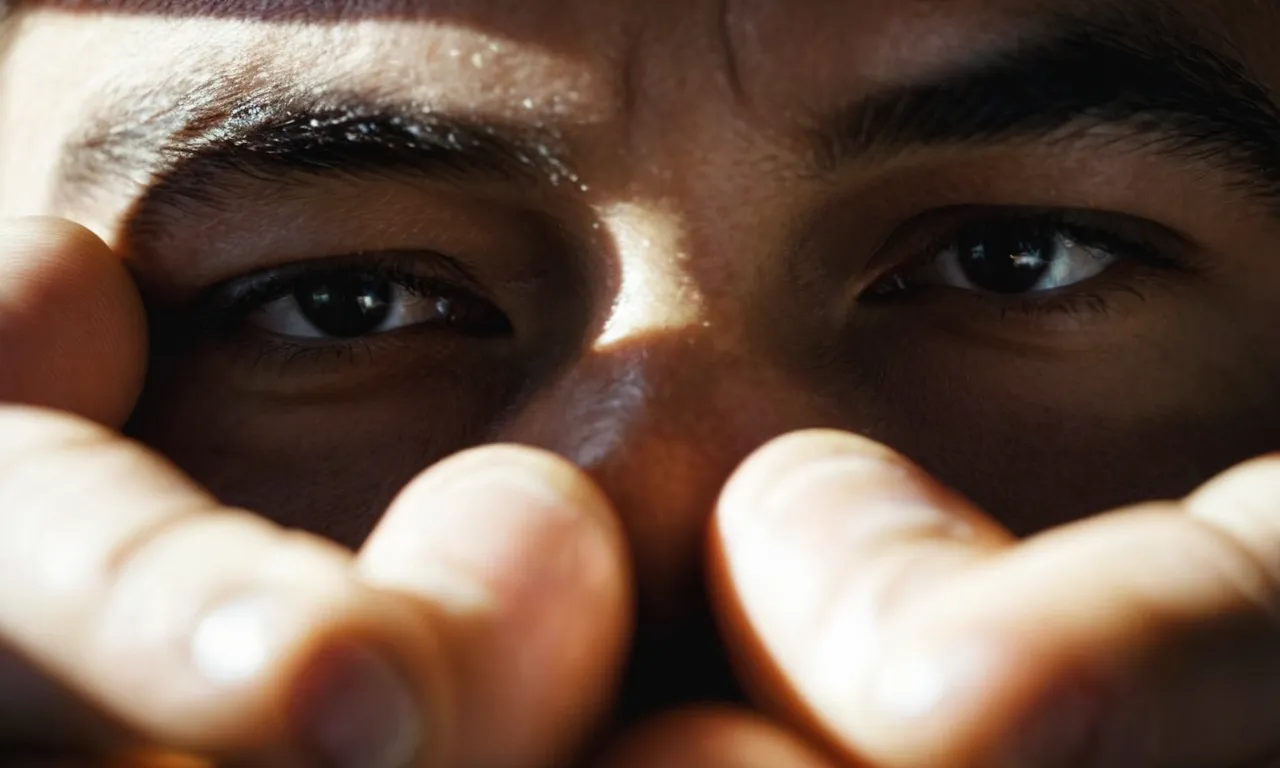 A close-up of a person's hands tightly holding a heavy burden, their face showing determination and a glimmer of hope, as rays of light shine through the darkness around them.