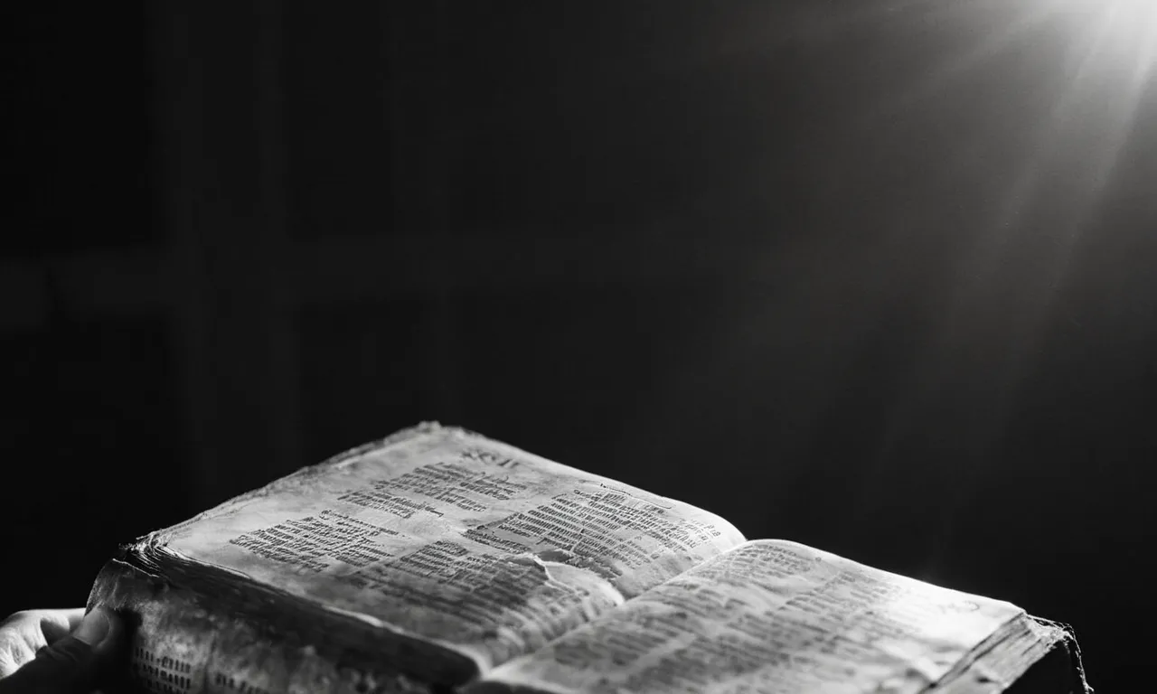 A black and white close-up of a weathered hand holding a worn Bible, depicting the universal message of Jesus's salvation for all humanity.