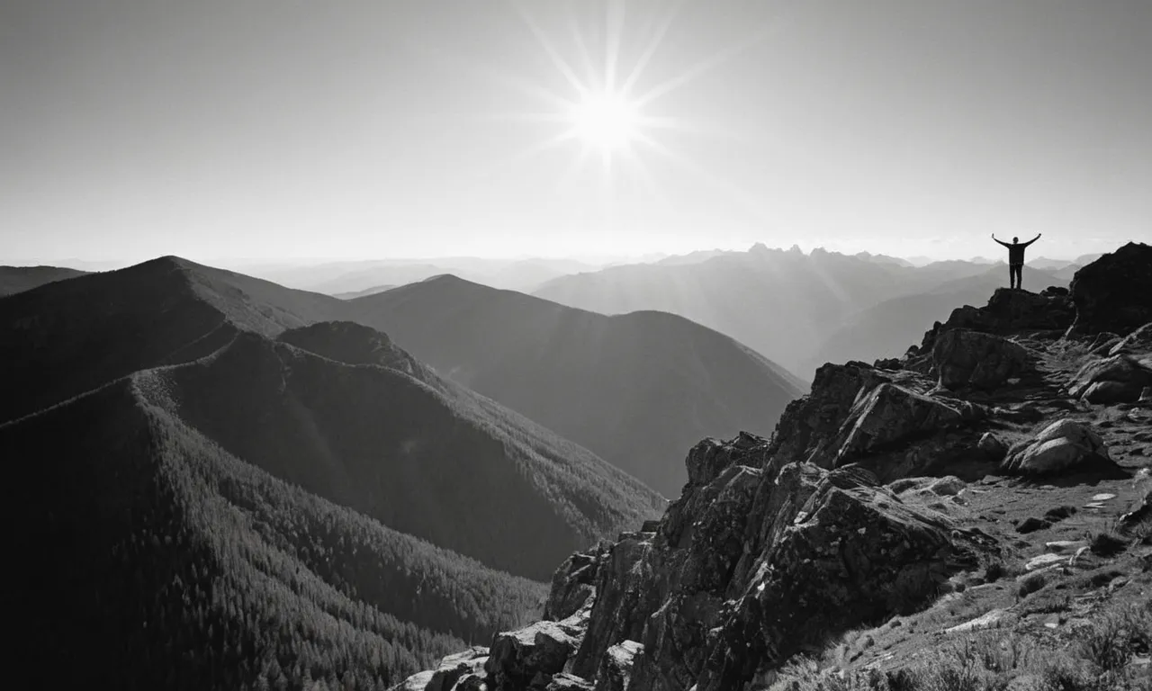 A black and white photograph capturing a person standing on a mountaintop, arms outstretched towards the sun, symbolizing their connection with nature and their personal interpretation of God.