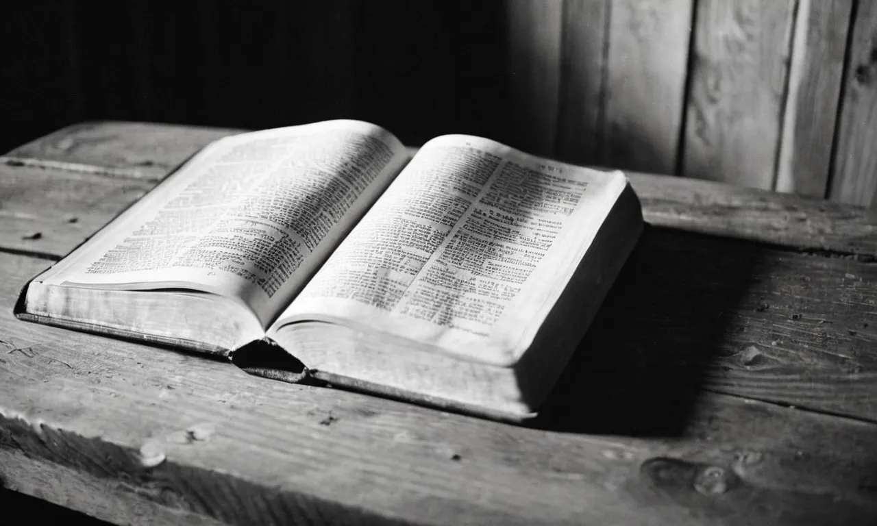 A black and white photo of a worn Bible lying open on a rustic wooden table, with a beam of soft light illuminating the page that states, "Who is the bridegroom?"