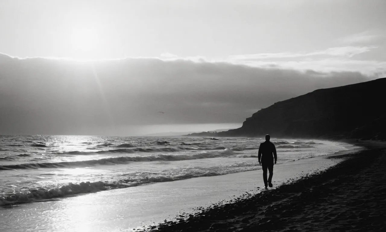 A black and white silhouette captures a solitary figure walking along a rugged shoreline at sunset, their silhouette merging with the horizon, symbolizing the journey of a soul who walked with God.