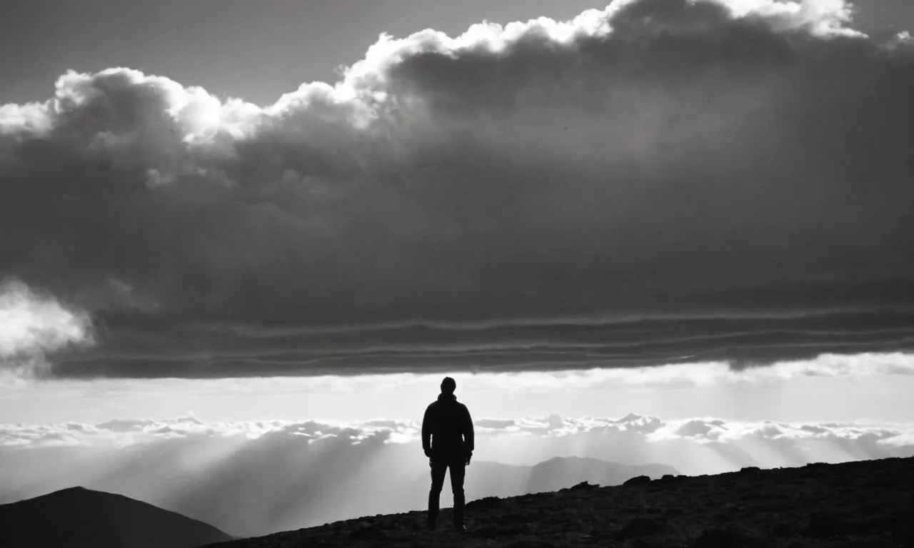 A black and white image of a person standing alone on a mountaintop, surrounded by clouds, with their hands cupped around their ears, seeking to hear a divine voice.
