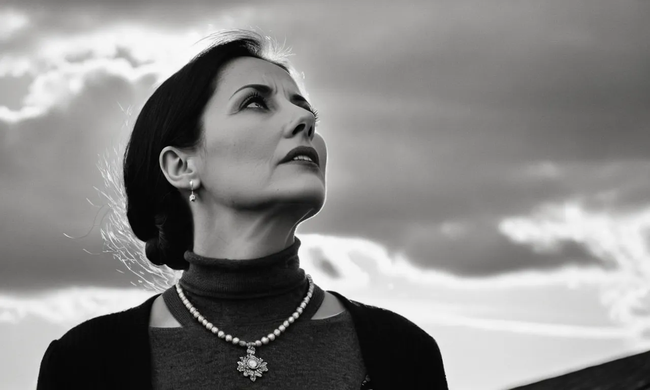 A black-and-white photograph captures a grieving widow standing alone, her eyes filled with pain and longing, as she looks up to the sky, questioning the purpose behind her loss.