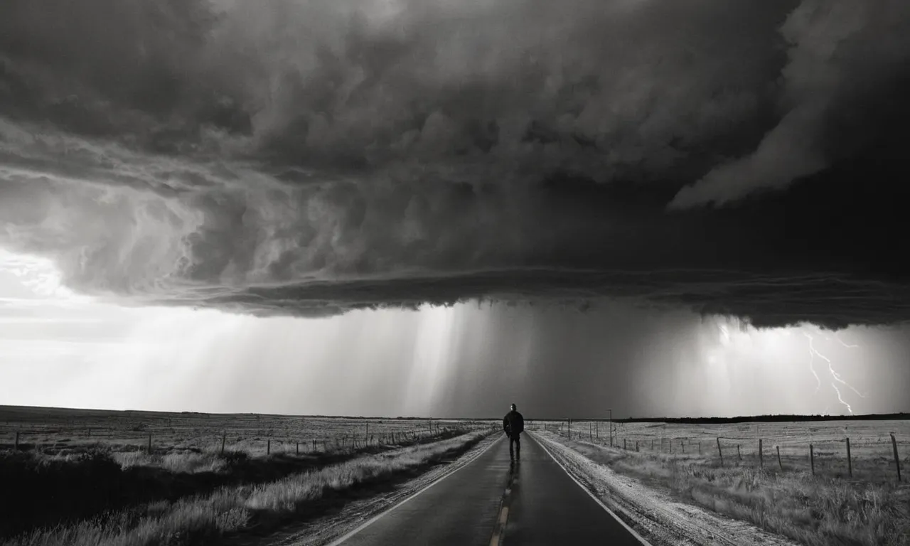 A black and white image captures Paul Thorn, standing tall amidst a chaotic storm, his unwavering faith symbolized by the rays of light piercing through dark clouds.