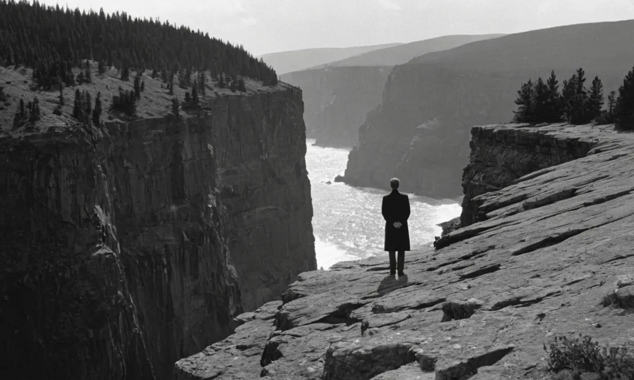A black-and-white image of a solitary figure standing at the edge of a cliff, their face filled with contemplation and despair, symbolizing the existential question of why human beings are destined to experience failure.